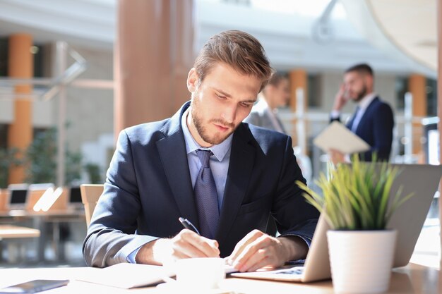 Retrato de joven sentado en su escritorio en la oficina.