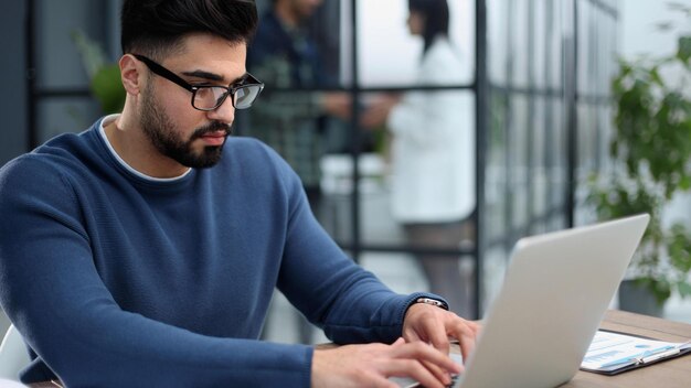 Retrato de un joven sentado en su escritorio en la oficina