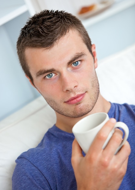 Retrato de un joven serio mirando a la cámara sosteniendo una taza