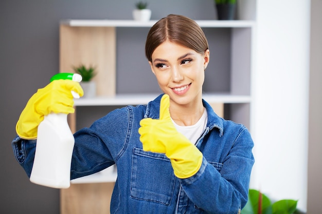 Retrato de una joven sirvienta feliz con productos de limpieza