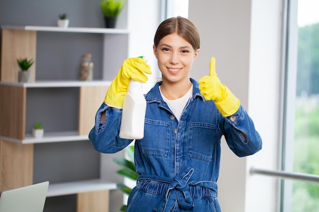 Retrato de una joven sirvienta feliz que está limpiando la oficina