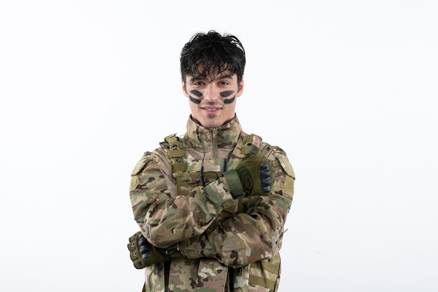 Retrato de joven soldado de camuflaje en la pared blanca