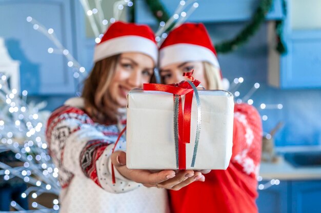 Foto retrato de una joven sonriente y una adolescente con un regalo de navidad en casa