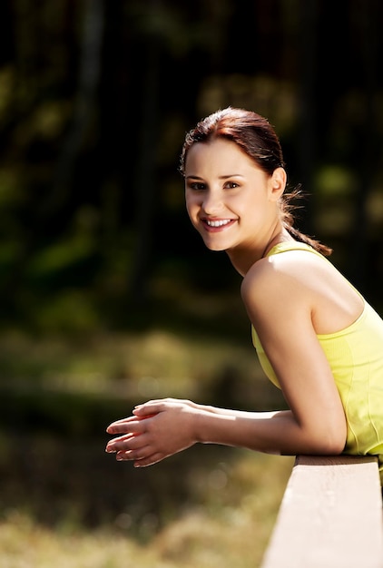 Retrato de una joven sonriente apoyándose en una barandilla al aire libre