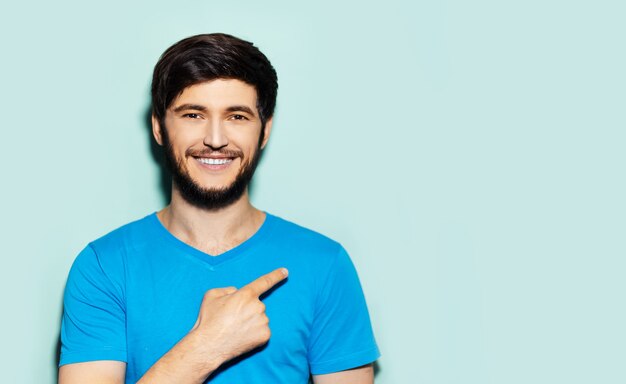 Retrato de joven sonriente con camisa azul, apuntando con el dedo