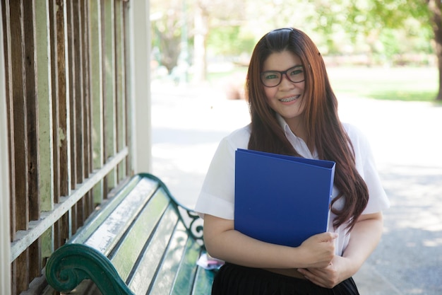 Foto retrato de una joven sonriente con una carpeta en el banco