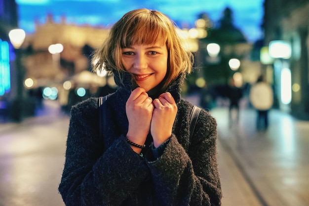 Retrato de una joven sonriente en la ciudad por la noche