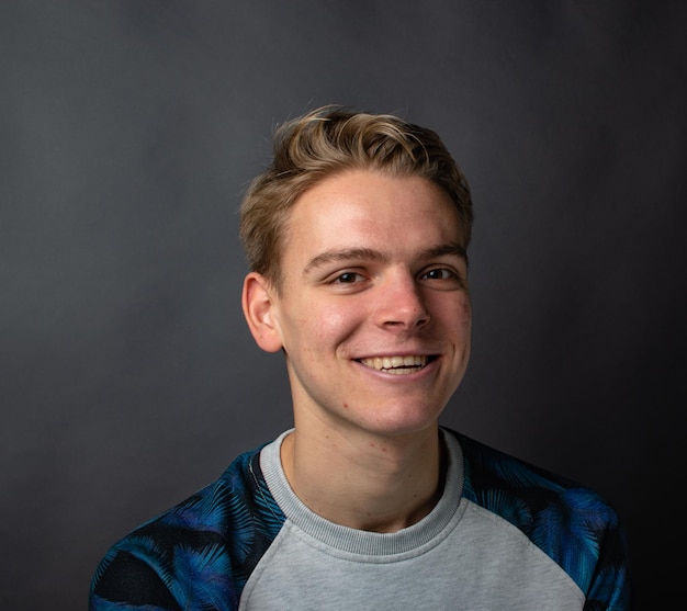 Foto retrato de un joven sonriente contra un fondo negro