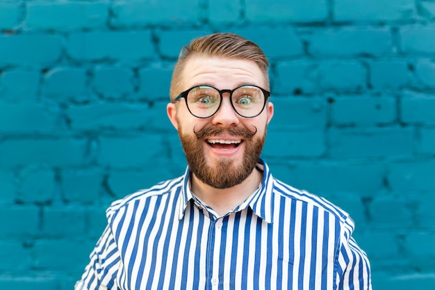 Retrato de un joven sonriente con estilo positivo positivo con bigote y barba con el telón de fondo de