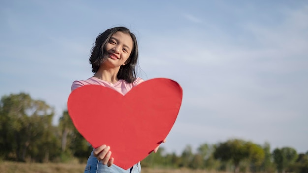 Foto retrato de una joven sonriente con forma de corazón contra el cielo