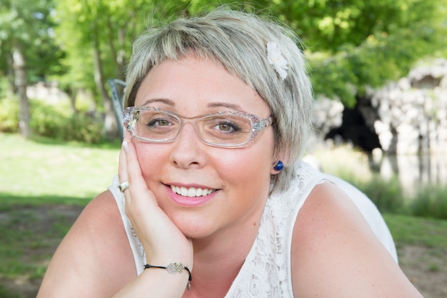 Retrato de una joven sonriente con gafas posando en el parque en la ciudad