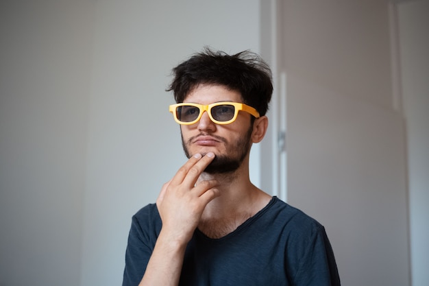 Retrato de joven sonriente con gafas de sol amarillas.