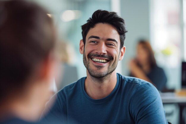 Foto retrato de un joven sonriente hablando con un colega durante una reunión en la oficina