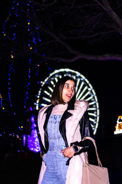 Retrato de una joven sonriente en Navidad visitando un parque de Navidad por la noche