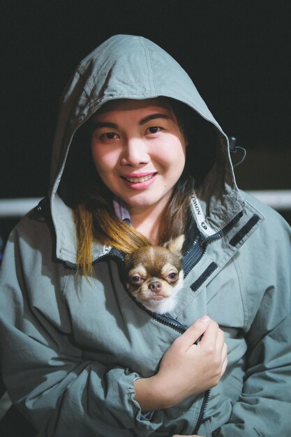 Retrato de una joven sonriente con un perro en una chaqueta