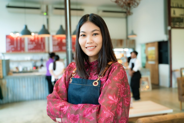 Foto retrato de una joven sonriente de pie en un café