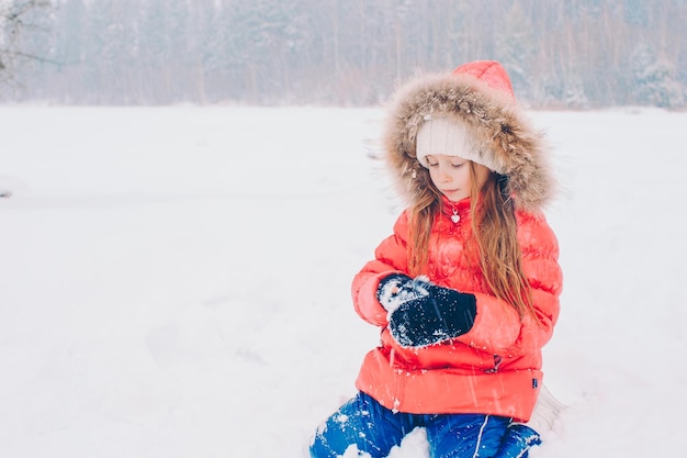 Foto retrato de una joven sonriente de pie en un campo cubierto de nieve