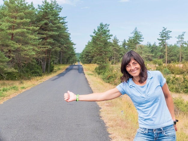 Foto retrato de una joven sonriente de pie en la carretera