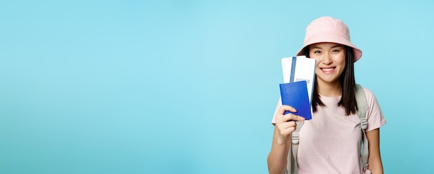 Foto retrato de una joven sonriente de pie contra un fondo azul