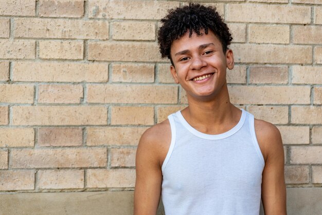 Foto retrato de un joven sonriente de pie contra una pared de ladrillo