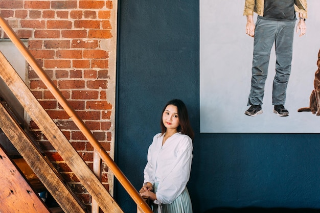 Foto retrato de una joven sonriente de pie contra la pared