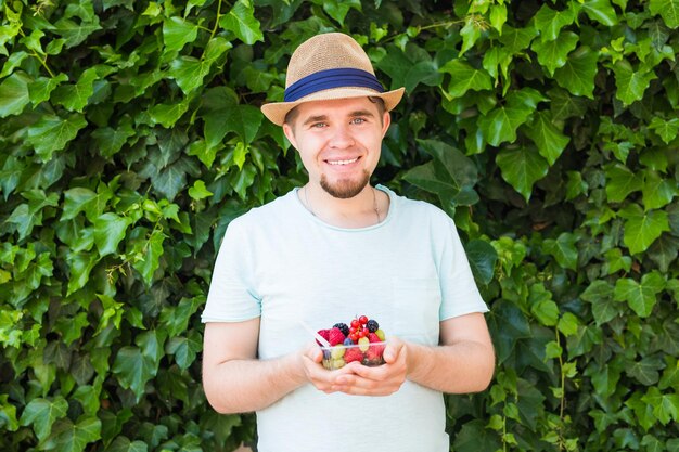 Foto retrato de un joven sonriente de pie contra las plantas