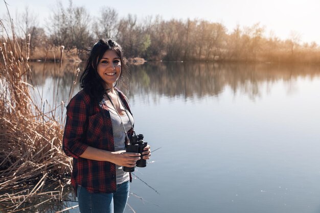 Foto retrato de una joven sonriente de pie junto al lago