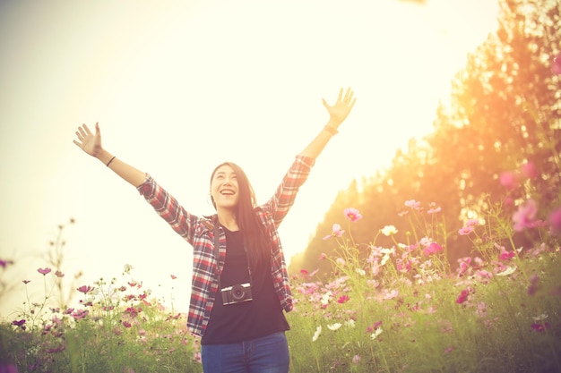 Retrato de una joven sonriente de pie junto a las flores contra un cielo despejado