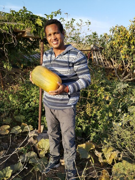 Foto retrato de una joven sonriente de pie junto a las plantas