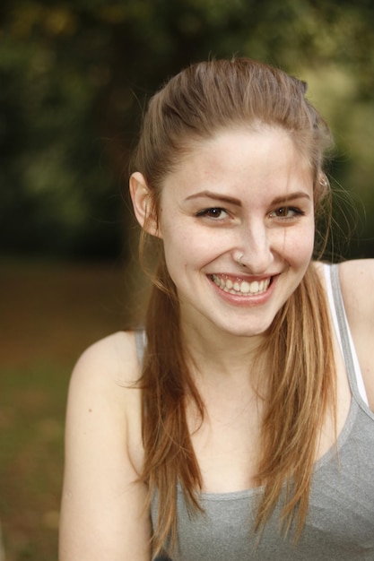 Foto retrato de una joven sonriente de pie en el parque