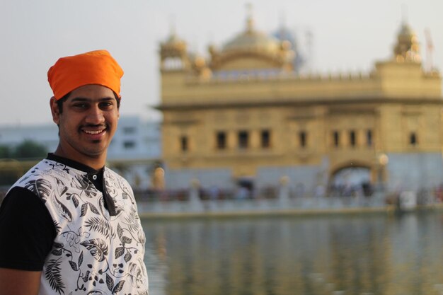 Foto retrato de un joven sonriente de pie en el templo dorado