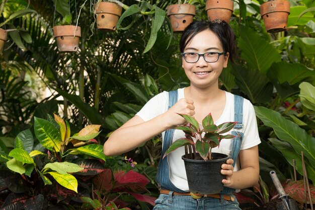 Foto retrato de una joven sonriente con plantas en maceta