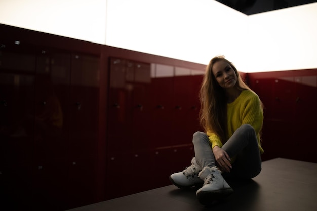 Foto retrato de una joven sonriente sentada contra la pared