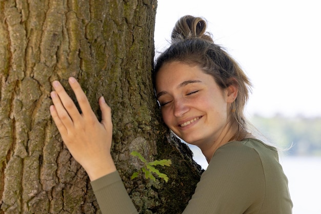 Foto retrato de una joven sonriente sentada en el tronco de un árbol