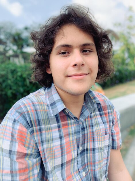 Foto retrato de un joven sonriente sentado al aire libre