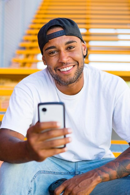 Retrato de un joven sonriente con un smartphone sentado en las escaleras