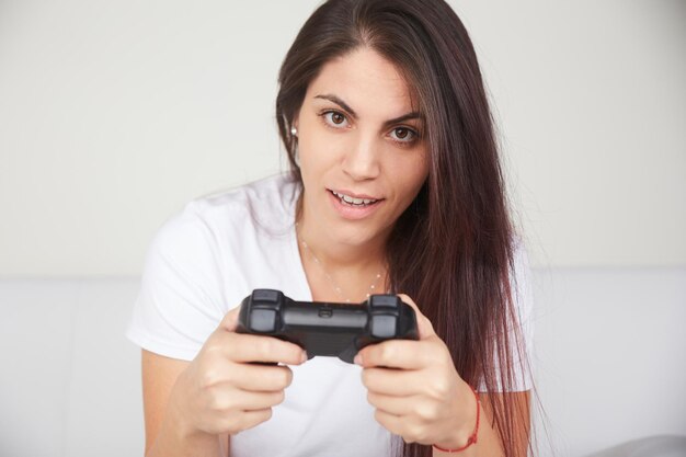 Foto retrato de una joven sonriente sosteniendo el control remoto de un videojuego