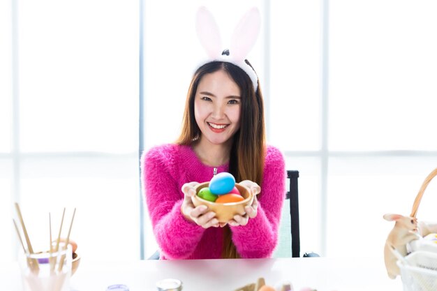 Foto retrato de una joven sonriente sosteniendo un cuenco con huevos de pascua