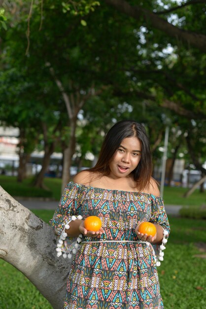 Foto retrato de una joven sonriente sosteniendo plantas contra los árboles