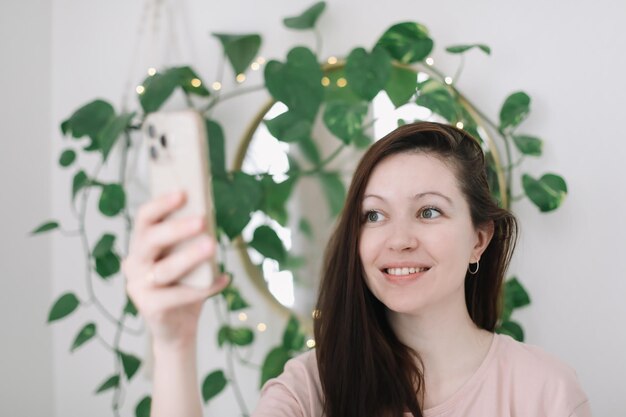 Retrato de una joven sonriente sosteniendo un teléfono inteligente haciendo selfie o chateando por video