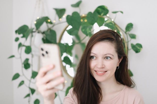 Retrato de una joven sonriente sosteniendo un teléfono inteligente haciendo selfie o chateando por video