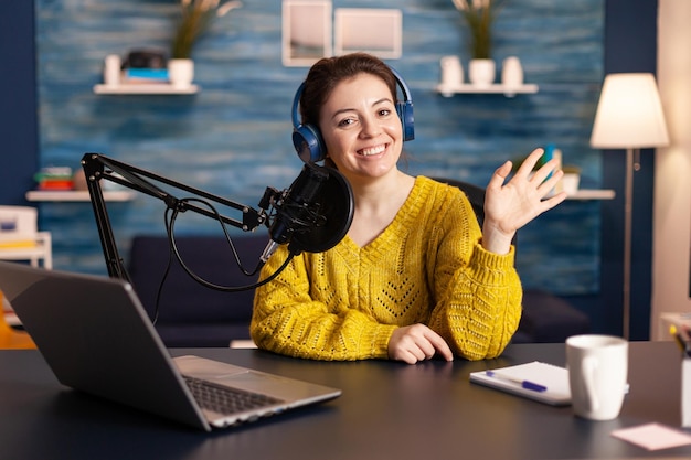 Retrato de una joven sonriente usando el teléfono mientras está sentada en la mesa