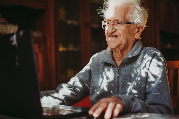 Retrato de un joven sonriente usando el teléfono mientras está sentado en la mesa