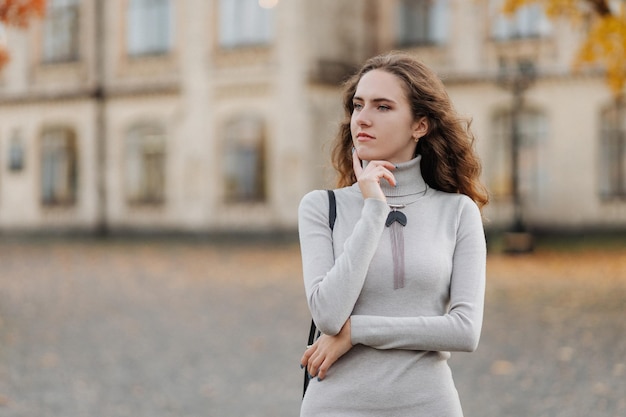 Retrato de joven sonriente con un vestido gris en el parque de otoño