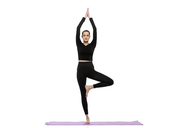 Retrato de joven soprtive chica haciendo ejercicios de yoga aislado sobre fondo blanco stuio