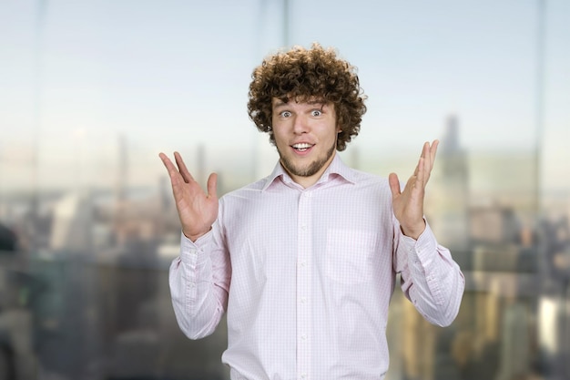 Retrato de un joven sorprendido con el cabello rizado paisaje urbano en el fondo