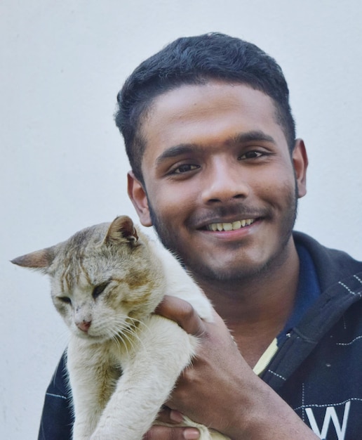 Foto retrato de un joven sosteniendo un gato.