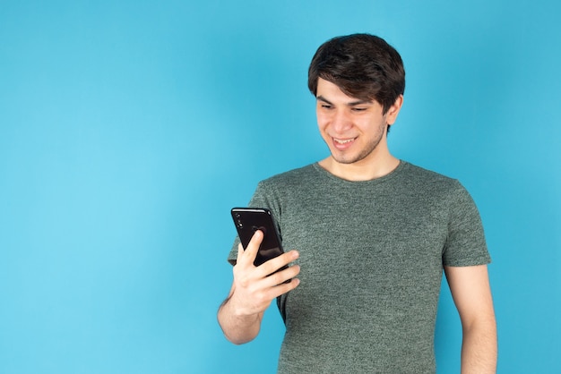 Retrato de un joven con un teléfono móvil contra el azul.