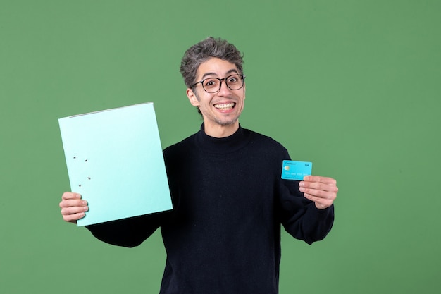 Foto retrato, de, joven, tenencia, documento, y, tarjeta de crédito, en, fondo verde, naturaleza, banco, maestro