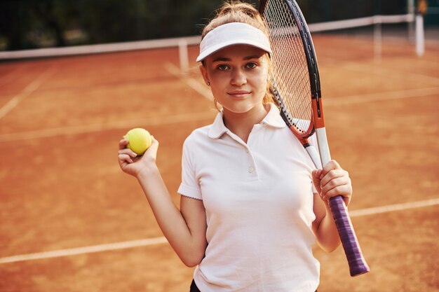 Retrato de joven tenista en ropa deportiva está en la cancha al aire libre.